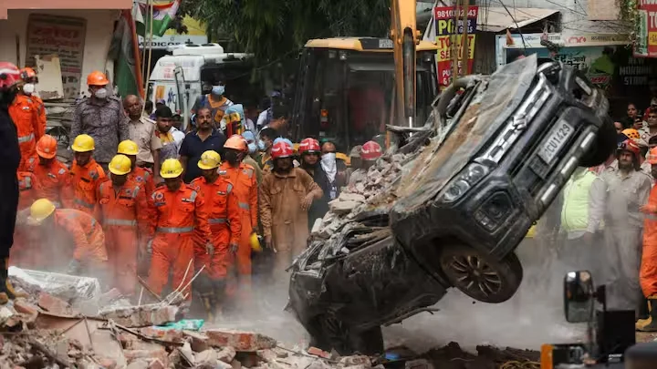 Debris and damaged vehicle at the base of the collapsed Satya Niketan building, showing basement-level destruction